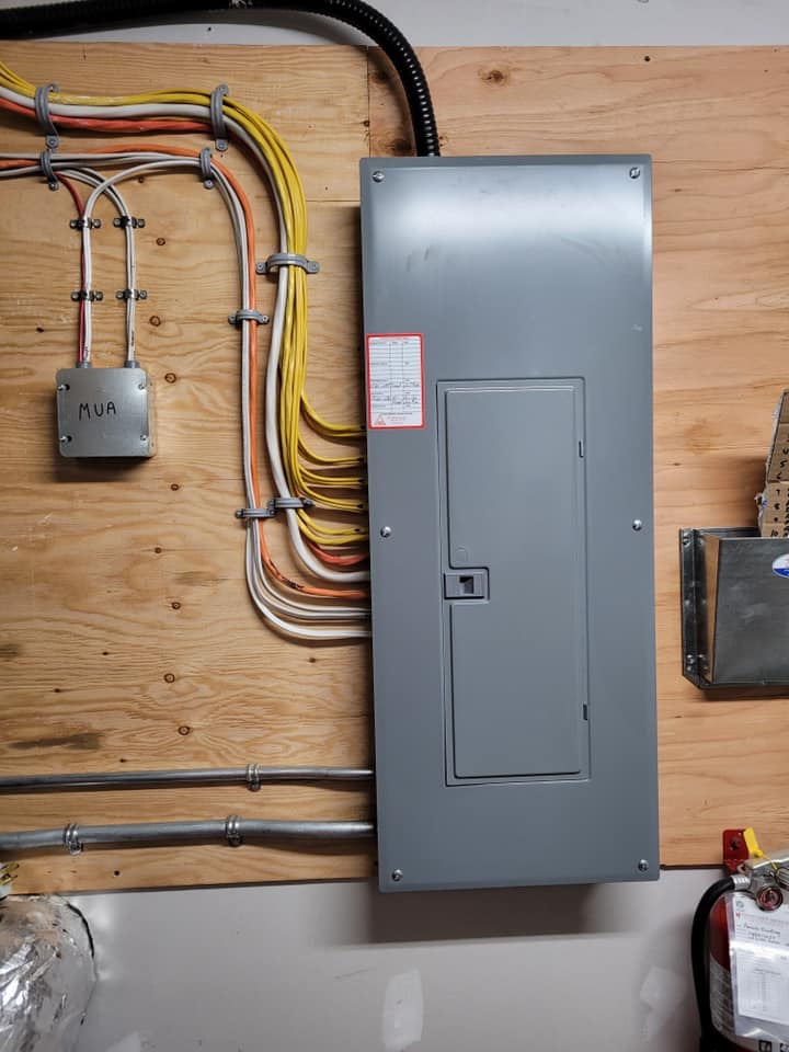 Breaker panel mounted on a plywood backboard with neatly routed wiring runs